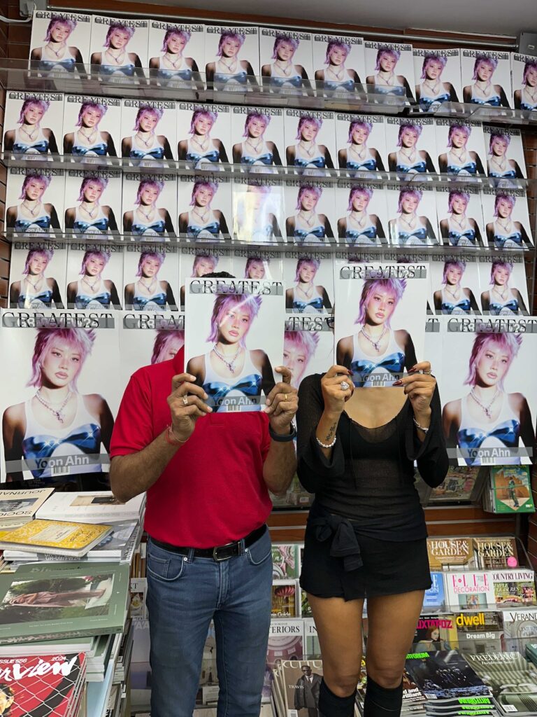 Yoon Ahn and Hemal Sheth holding The Greatest Issue 09 over their faces at Iconic Magazines, Mulberry Street