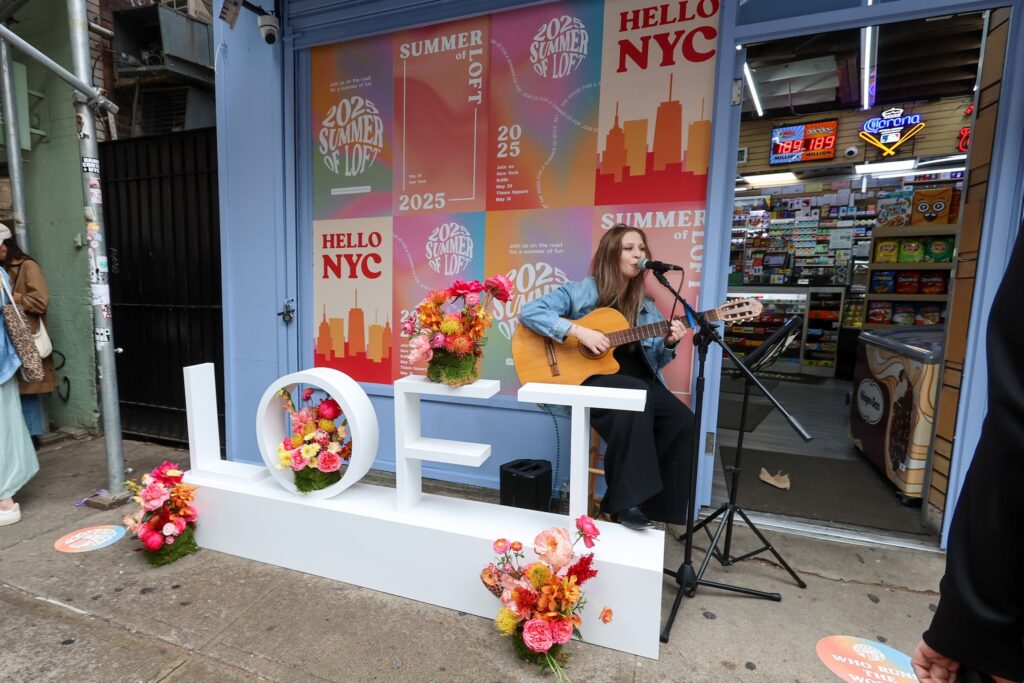Musician performing beside the floral LOFT display at the Summer of LOFT pop-up
